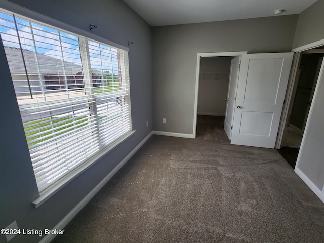 unfurnished bedroom with multiple windows, a closet, a spacious closet, and carpet flooring