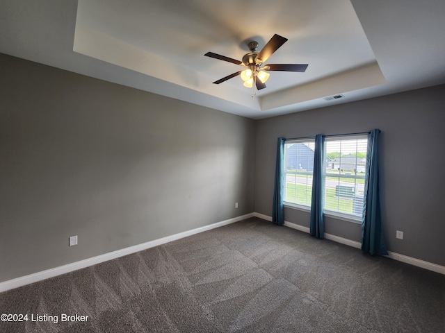 carpeted spare room with ceiling fan and a tray ceiling