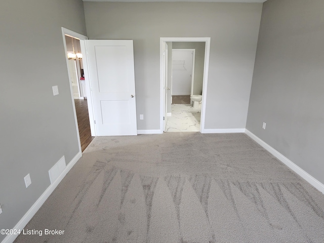 unfurnished bedroom featuring light carpet and connected bathroom