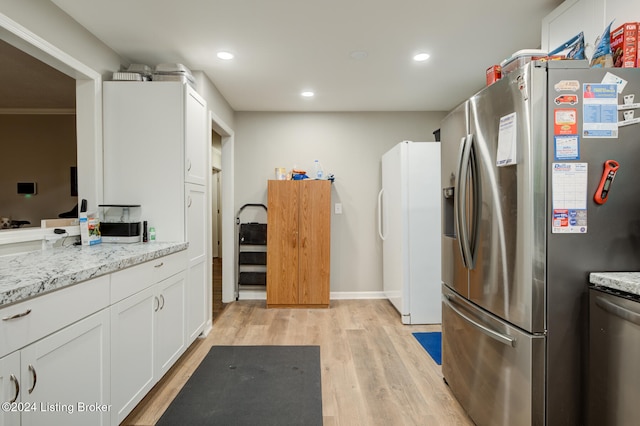 kitchen featuring white cabinetry, light wood-type flooring, appliances with stainless steel finishes, and light stone countertops