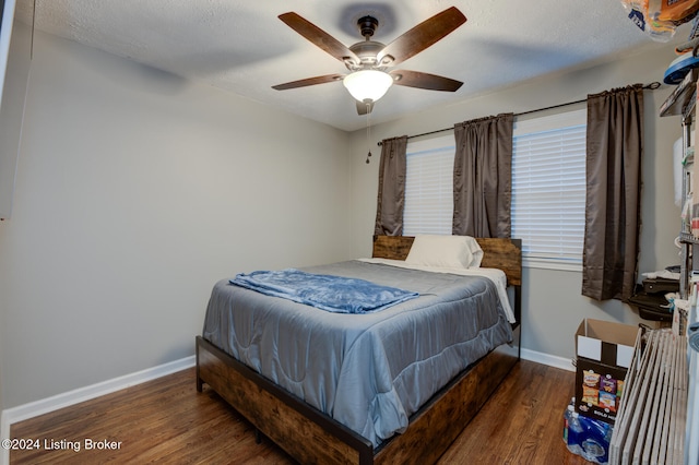 bedroom with dark hardwood / wood-style flooring, a textured ceiling, and ceiling fan