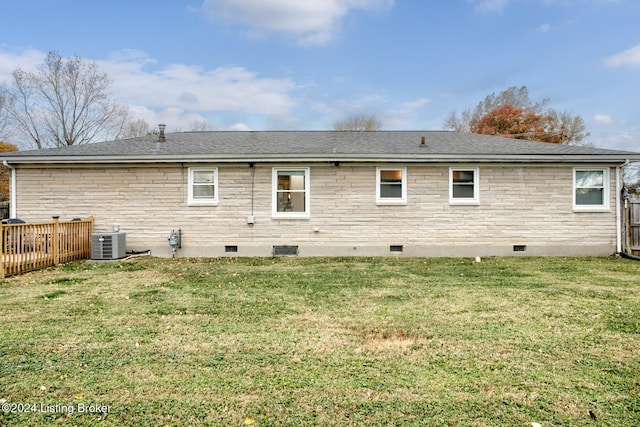 rear view of house featuring central AC unit and a yard