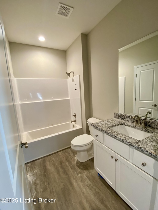 bathroom with visible vents, toilet, wood finished floors, vanity, and shower / washtub combination