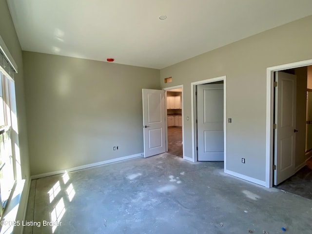 unfurnished bedroom with concrete floors and baseboards