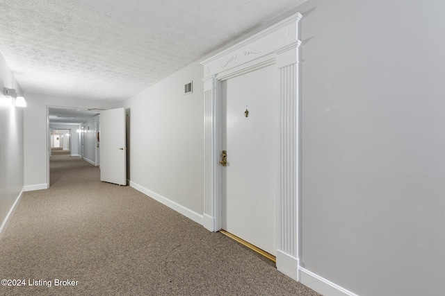 hallway featuring a textured ceiling and carpet