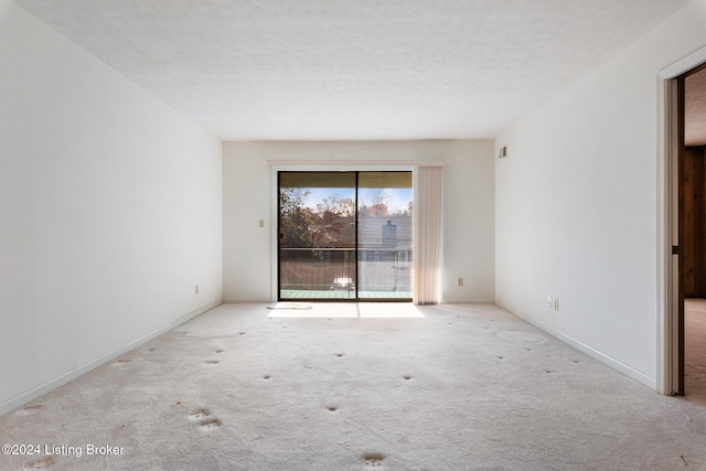 empty room with a textured ceiling and light carpet