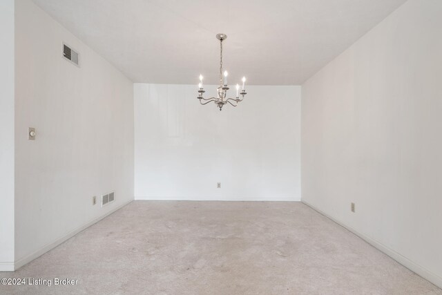 spare room with a chandelier and light colored carpet