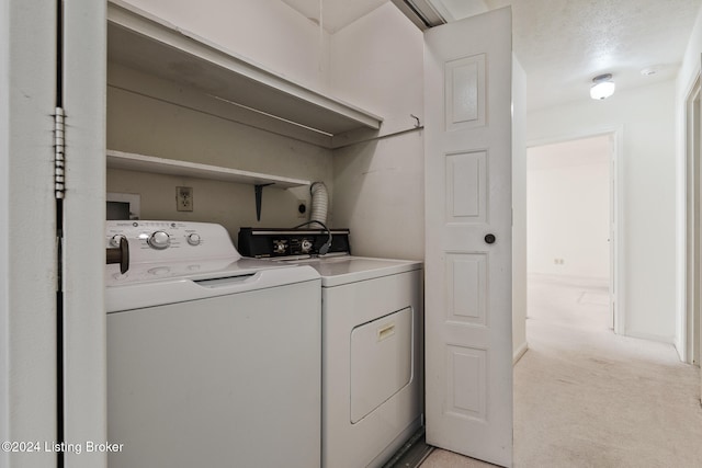 washroom featuring washer and dryer, a textured ceiling, and light carpet