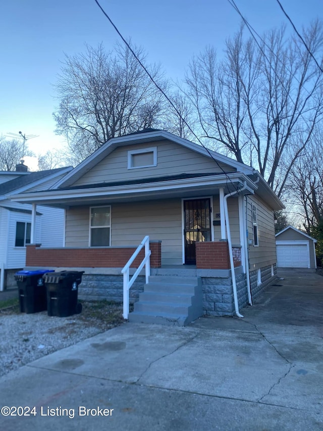 bungalow with covered porch, a garage, and an outbuilding