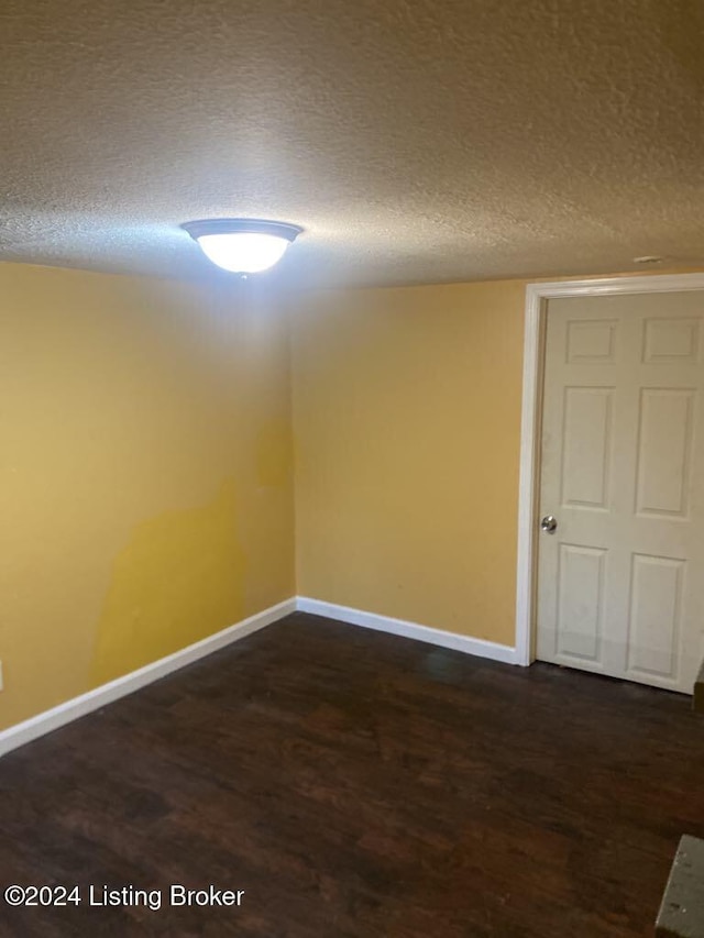 spare room featuring a textured ceiling and dark hardwood / wood-style floors