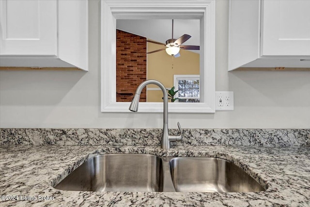 room details featuring white cabinets, light stone countertops, ceiling fan, and sink