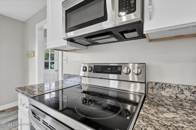 kitchen with white cabinets, stainless steel appliances, dark wood-type flooring, and dark stone countertops