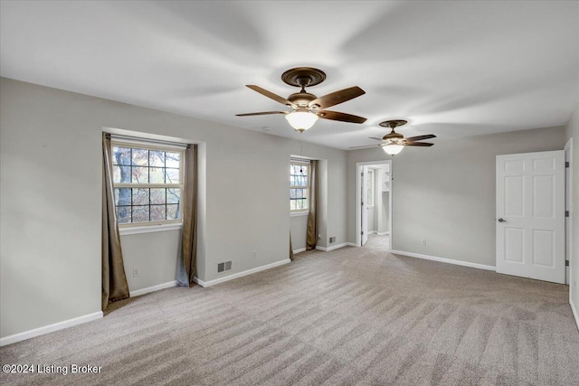 empty room with ceiling fan, a healthy amount of sunlight, and light carpet