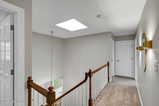 hallway featuring a skylight and light carpet