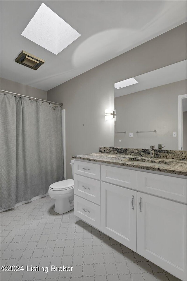 bathroom with vanity, toilet, and a skylight