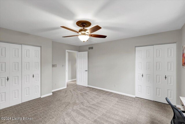 unfurnished bedroom with multiple closets, light carpet, and ceiling fan