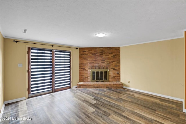 unfurnished living room featuring ornamental molding, wood-type flooring, a brick fireplace, and a textured ceiling