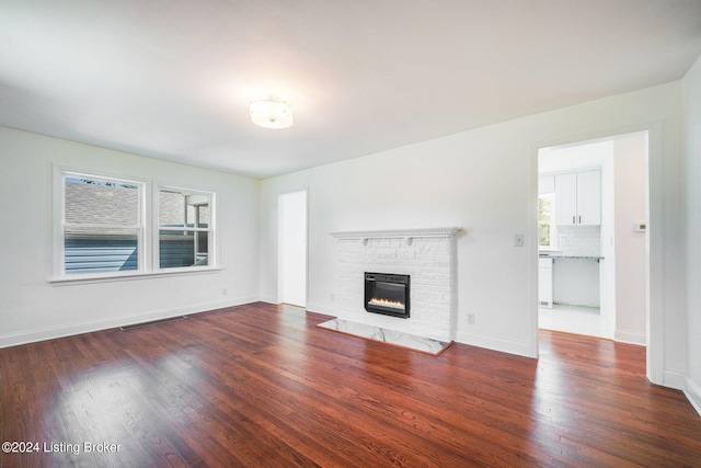 unfurnished living room with a wealth of natural light, a fireplace, and dark hardwood / wood-style flooring