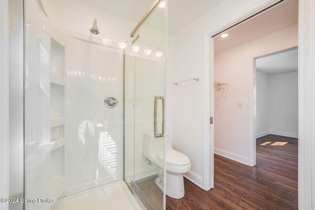 bathroom with toilet, a shower with door, and hardwood / wood-style floors