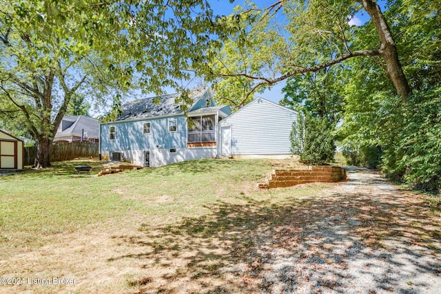 exterior space featuring a storage unit, a sunroom, and a lawn