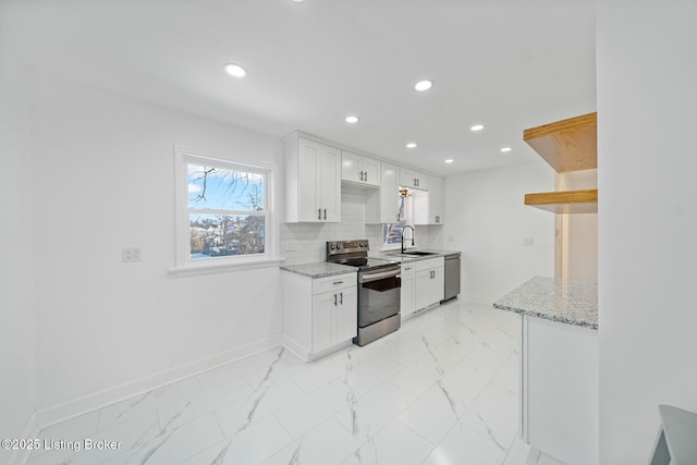 kitchen with sink, white cabinets, decorative backsplash, light stone counters, and stainless steel appliances