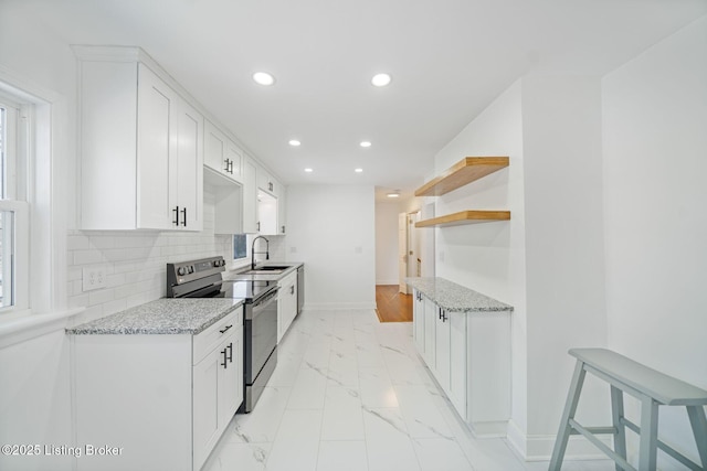 kitchen with white cabinetry, stainless steel electric range oven, sink, and light stone counters