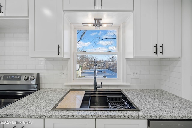 kitchen with electric stove, sink, decorative backsplash, and white cabinets