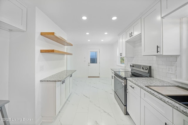 kitchen with light stone counters, decorative backsplash, stainless steel electric stove, and white cabinets