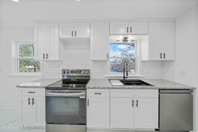 kitchen featuring sink, stainless steel range with electric stovetop, dishwasher, light stone countertops, and white cabinets