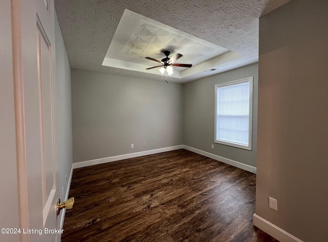 spare room featuring dark hardwood / wood-style flooring, ceiling fan, and a tray ceiling