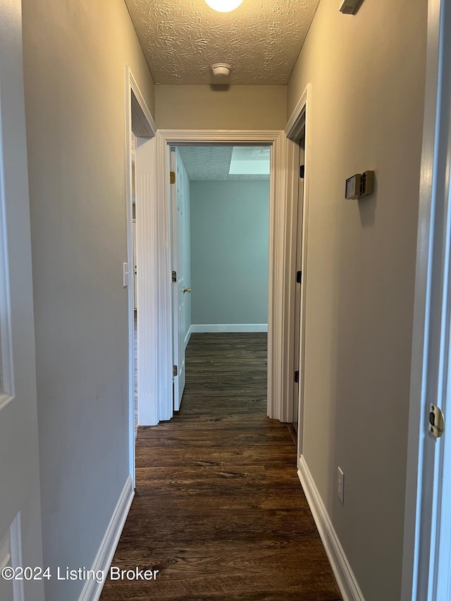 corridor featuring dark wood-type flooring and a textured ceiling