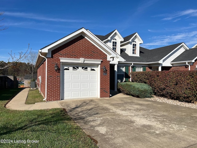 view of front of house with a garage, central AC unit, and a front yard