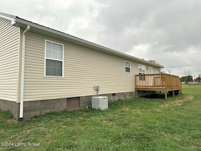 view of side of property with a deck, central air condition unit, and a yard