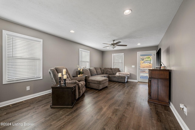 living room with ceiling fan, a textured ceiling, and dark hardwood / wood-style floors