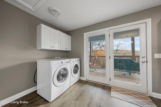 clothes washing area with hardwood / wood-style floors, cabinets, and washing machine and clothes dryer