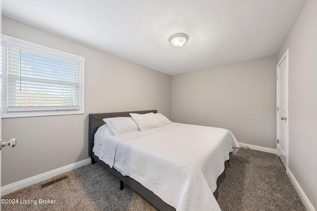 bedroom with dark colored carpet and a textured ceiling