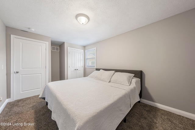 bedroom with a textured ceiling and dark carpet