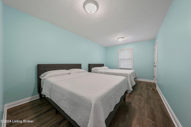 bedroom featuring a textured ceiling and dark hardwood / wood-style floors
