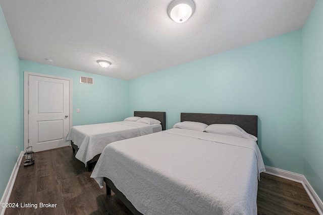 bedroom featuring dark wood-type flooring and a textured ceiling