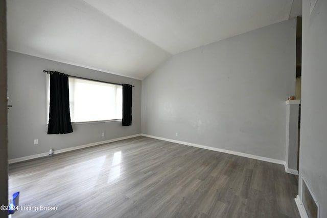 unfurnished room with lofted ceiling and hardwood / wood-style flooring