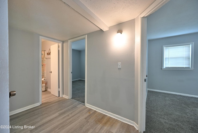 hallway with hardwood / wood-style floors, a textured ceiling, and beam ceiling