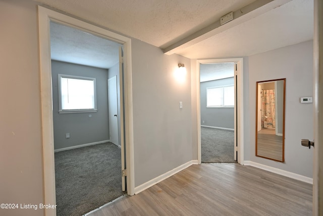 corridor with a textured ceiling and light hardwood / wood-style flooring