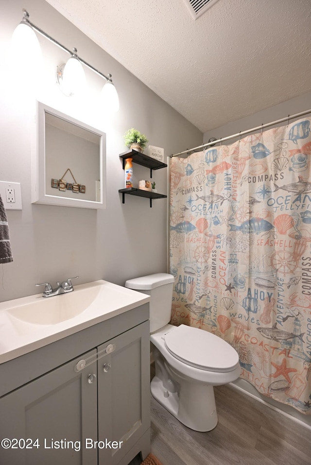 bathroom with a textured ceiling, curtained shower, wood-type flooring, vanity, and toilet