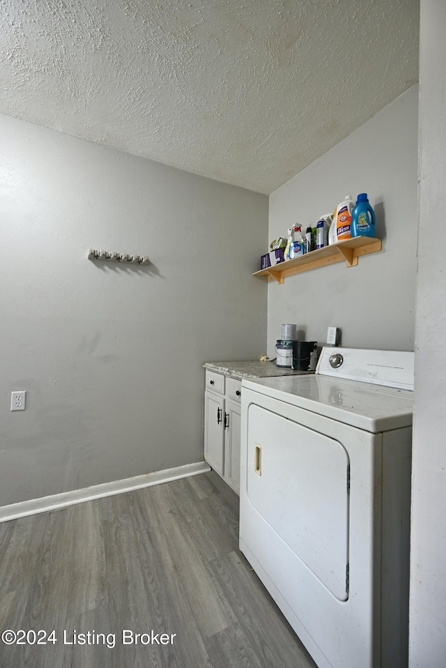 laundry room featuring washer / clothes dryer, light wood-type flooring, cabinets, and a textured ceiling