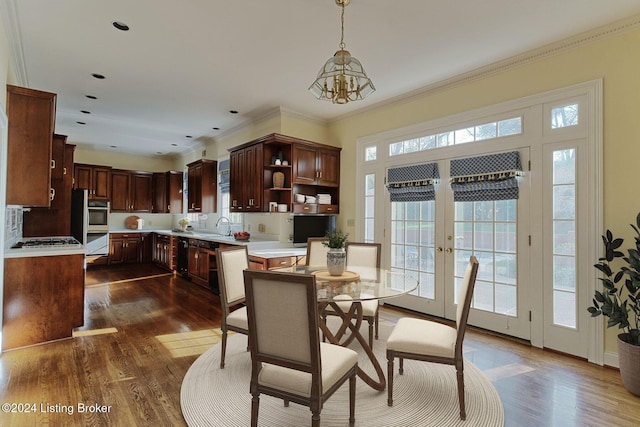 dining room with sink, a notable chandelier, dark hardwood / wood-style flooring, and ornamental molding