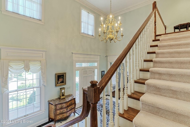 foyer entrance featuring ornamental molding, hardwood / wood-style floors, a chandelier, and a high ceiling