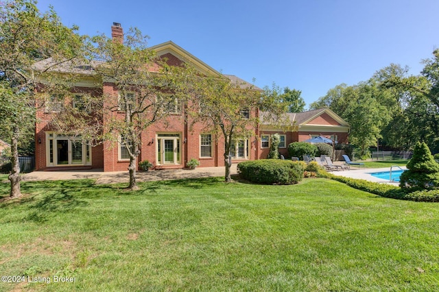 back of property featuring a lawn, a fenced in pool, and a patio area