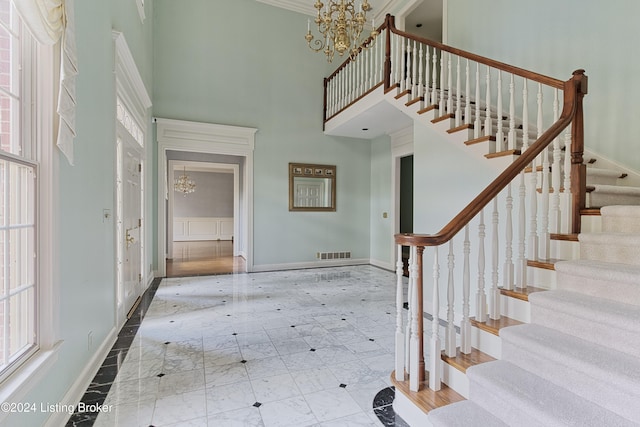 entrance foyer with a high ceiling, an inviting chandelier, and crown molding