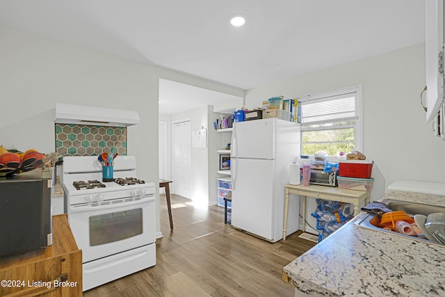 kitchen with white appliances, custom exhaust hood, and light hardwood / wood-style flooring