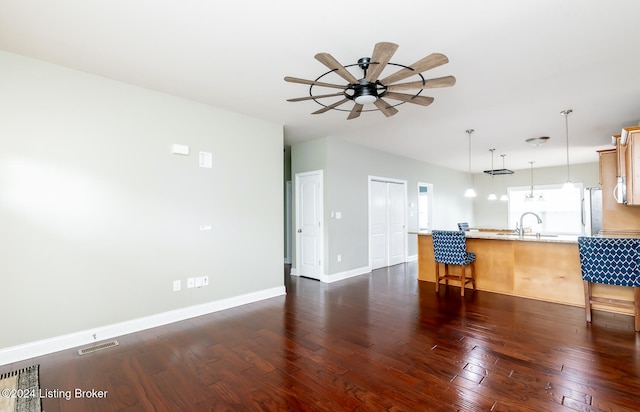 kitchen featuring kitchen peninsula, sink, decorative light fixtures, and dark hardwood / wood-style flooring